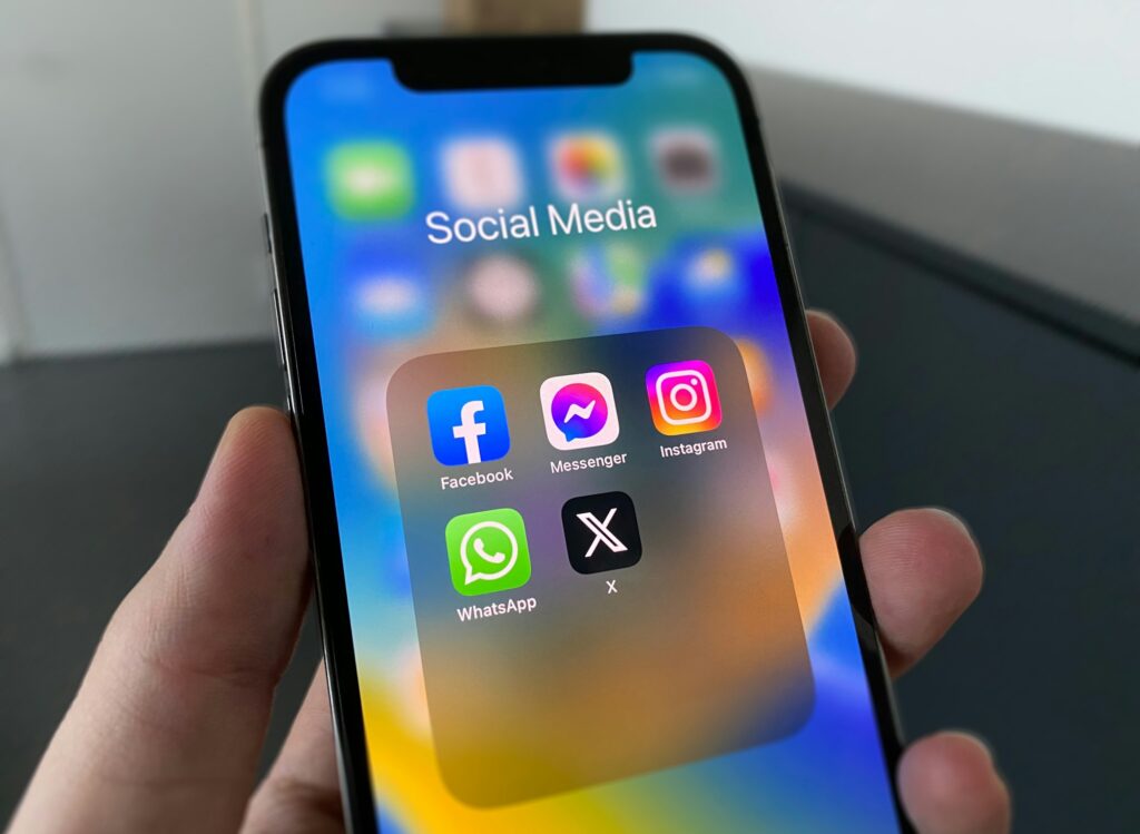 A person holding a cell phone with social media on the screen